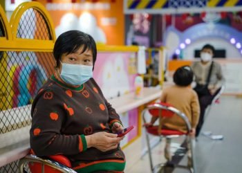 Una mujer protegida con una mascarilla utiliza su móvil en un centro comercial de Pekín este 11 de enero de 2023. Foto; Wu Hao / EFE.